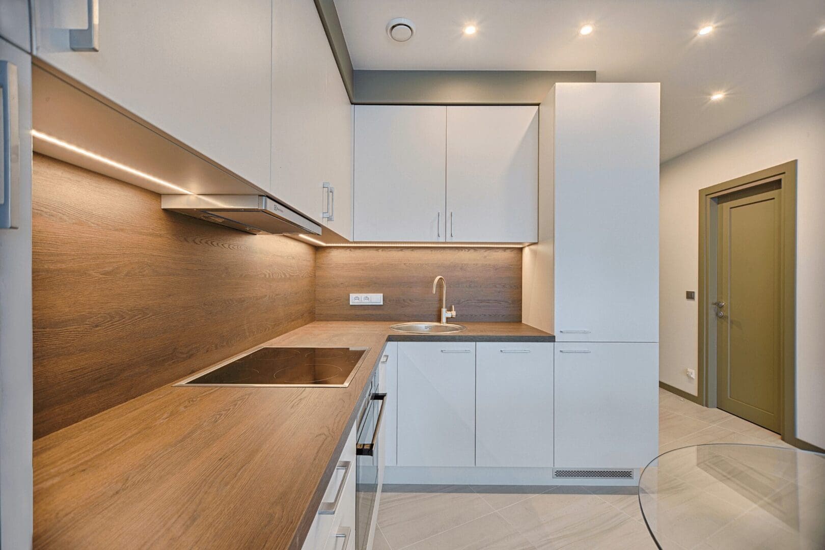 A kitchen with white cabinets and wood countertops.